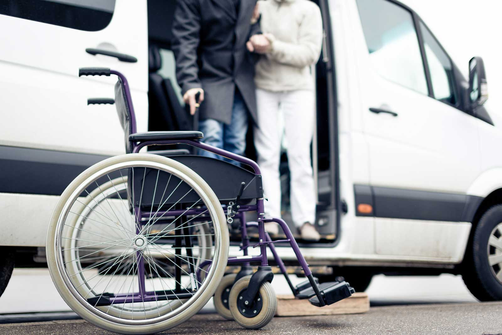 Nurse helping senior man exit a van