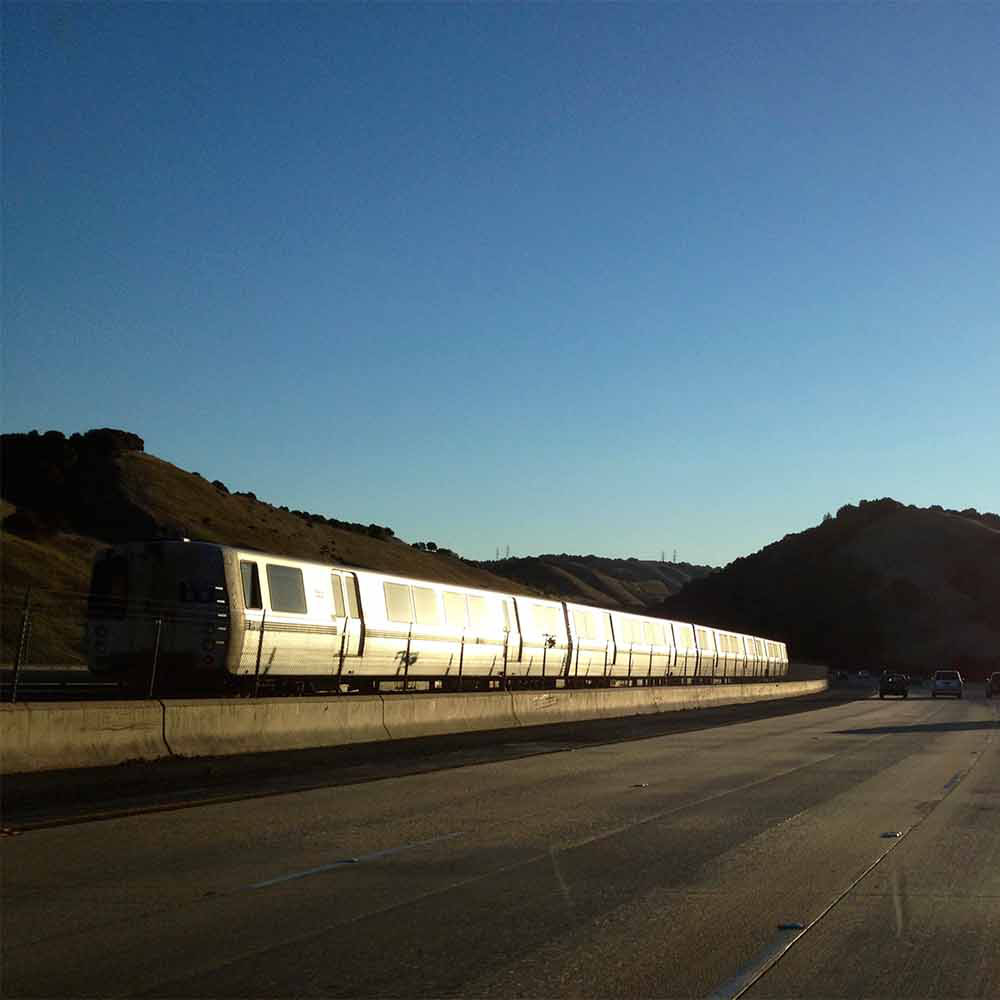 Bart Train on track along highway surrounded by mountains in Northern California