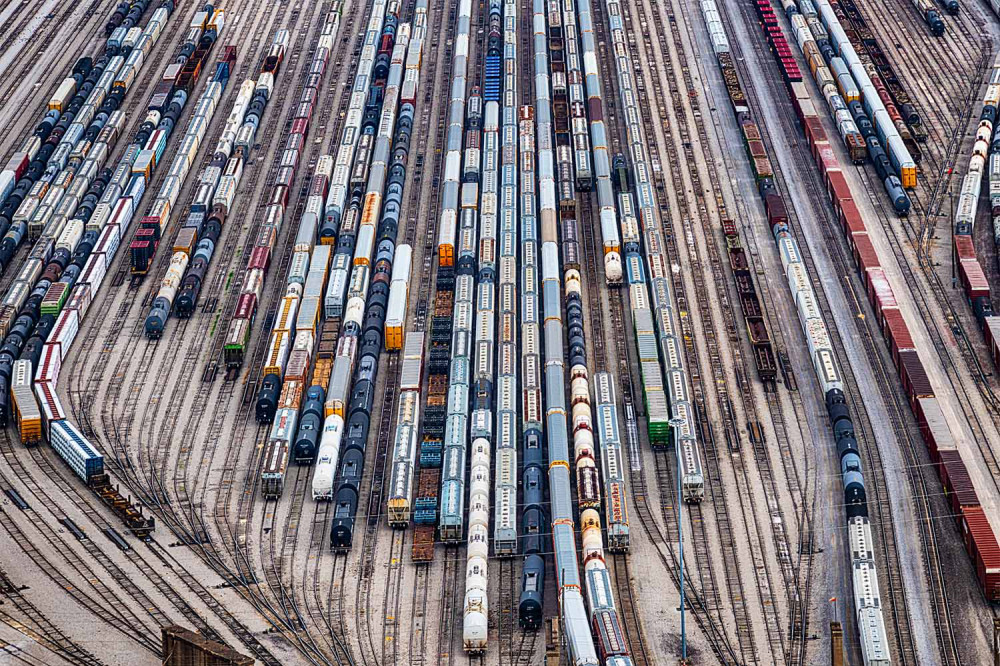 Aerial view of rail yard with lots of converging tracks and different kinds of trains.